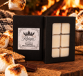 Reign Candle Toasted Marshmallow wax melts in black packaging beside toasted marshmallows and a fireplace